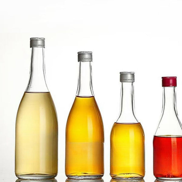 Row of clear glass bottles with screw caps filled with oil, vinegar and red syrup