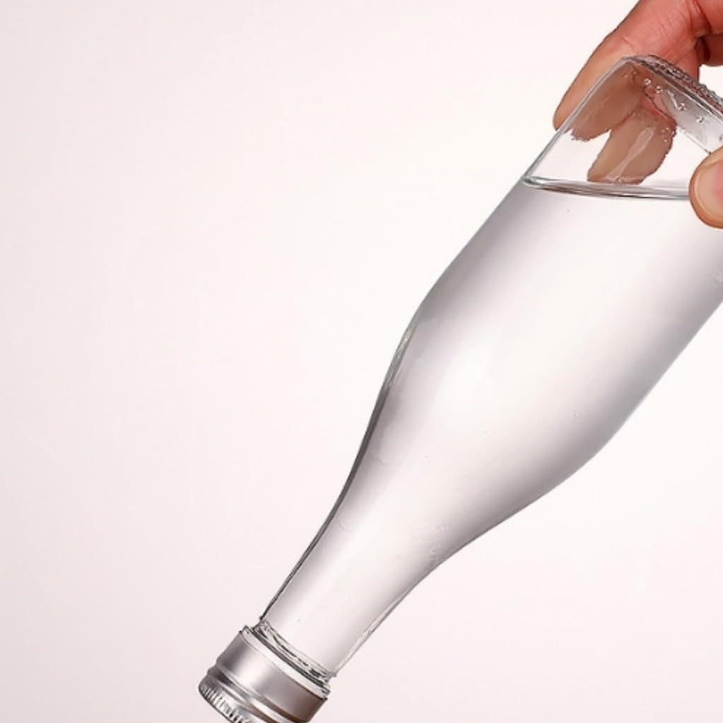 Hand holding an empty clear 200 ml glass bottle with screw cap